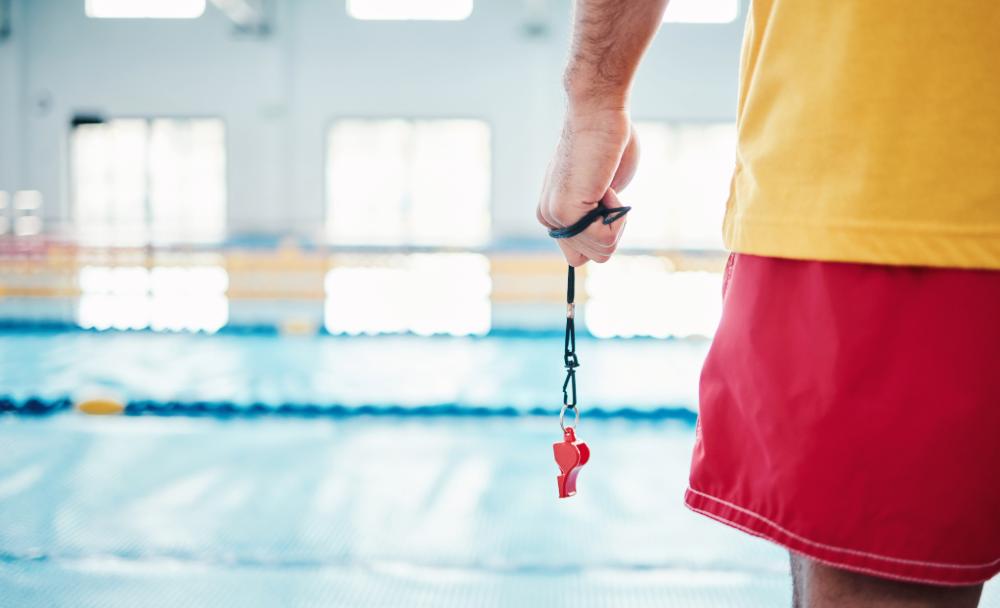 Lifeguard And Swim Instructor standing at pool with whistle